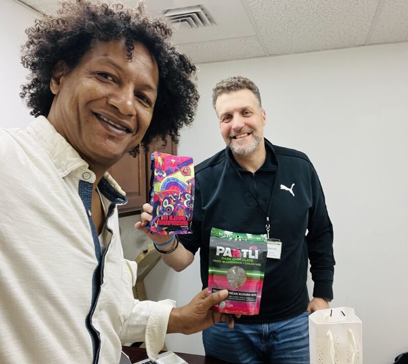 LaRon with a colleague holding coffee and chocolate products